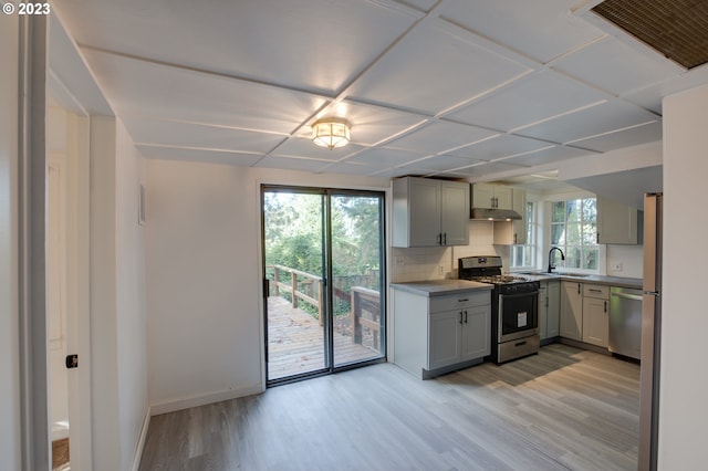 kitchen featuring gas range oven, gray cabinetry, dishwasher, backsplash, and light hardwood / wood-style flooring