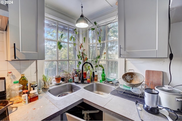 kitchen with gray cabinetry, backsplash, sink, and crown molding