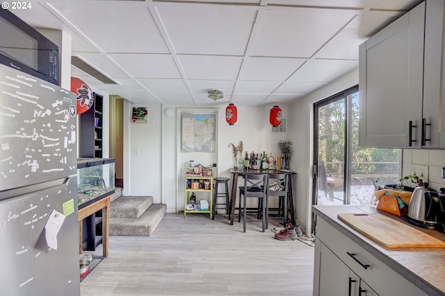 interior space with a drop ceiling and light hardwood / wood-style floors