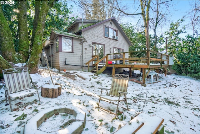 snow covered back of property with a deck