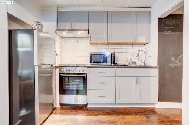 kitchen with appliances with stainless steel finishes, sink, backsplash, and dark hardwood / wood-style flooring