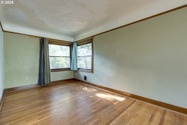 empty room featuring wood-type flooring and crown molding