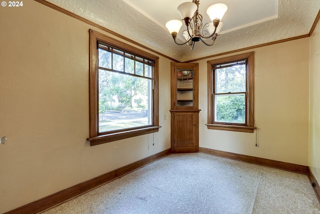 empty room featuring crown molding, plenty of natural light, a textured ceiling, and a notable chandelier