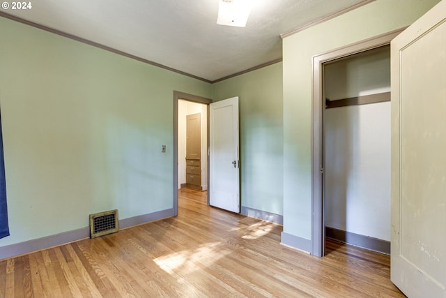 unfurnished bedroom with light hardwood / wood-style floors, a closet, and ornamental molding