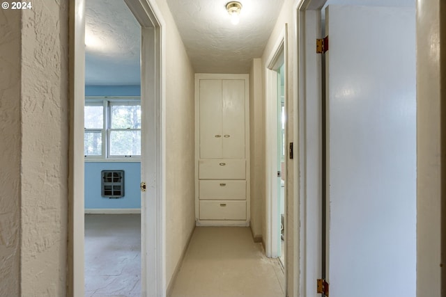 corridor with a textured ceiling and heating unit