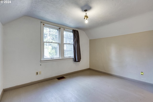 bonus room featuring light wood-type flooring, lofted ceiling, and a textured ceiling