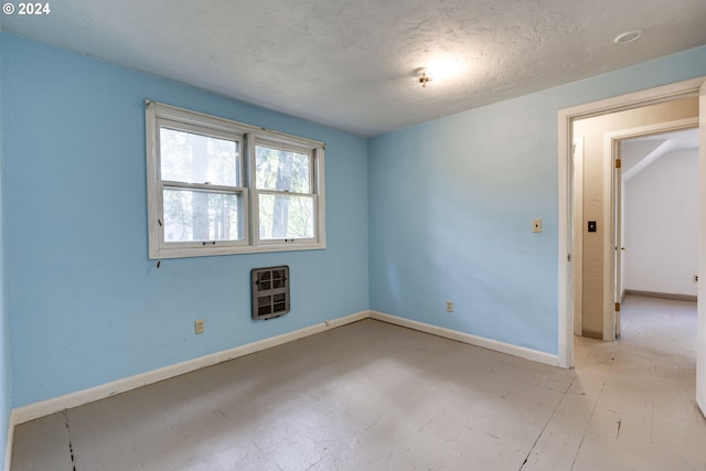 spare room with a textured ceiling and heating unit