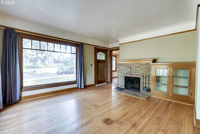 unfurnished living room with ornamental molding, a fireplace, and light hardwood / wood-style flooring