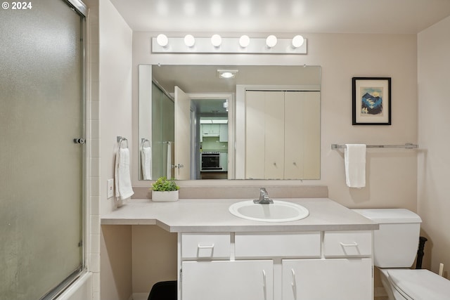 full bathroom featuring vanity, combined bath / shower with glass door, and toilet