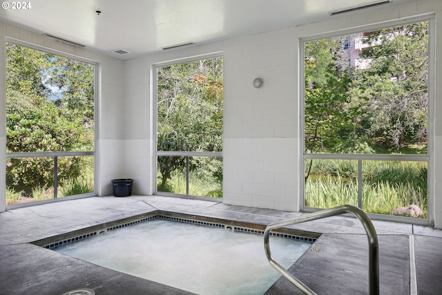 unfurnished sunroom featuring a jacuzzi and a healthy amount of sunlight