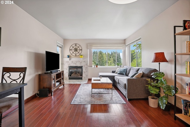 living room with a high end fireplace and dark wood-type flooring