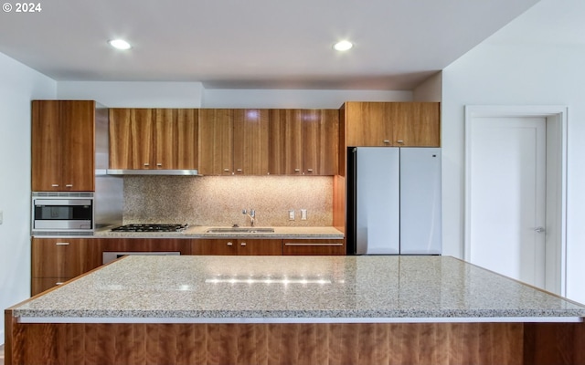 kitchen with tasteful backsplash, appliances with stainless steel finishes, brown cabinetry, modern cabinets, and a sink