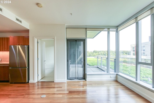 interior space with baseboards, visible vents, light wood-style flooring, freestanding refrigerator, and brown cabinets