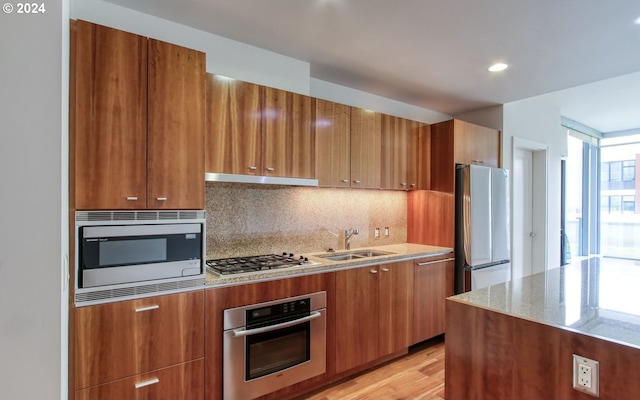 kitchen featuring a sink, stainless steel appliances, brown cabinets, and modern cabinets