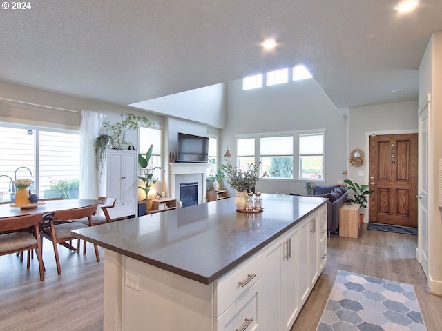 kitchen featuring white cabinetry, light hardwood / wood-style flooring, a textured ceiling, and a kitchen island