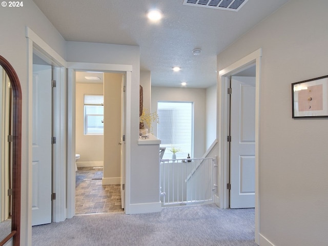 hall featuring a textured ceiling and light carpet