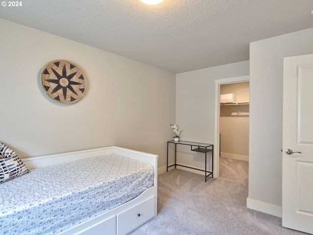 carpeted bedroom featuring a closet, a spacious closet, and a textured ceiling