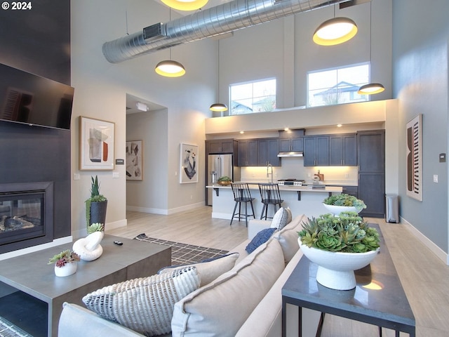 living room with sink, light hardwood / wood-style floors, and a towering ceiling