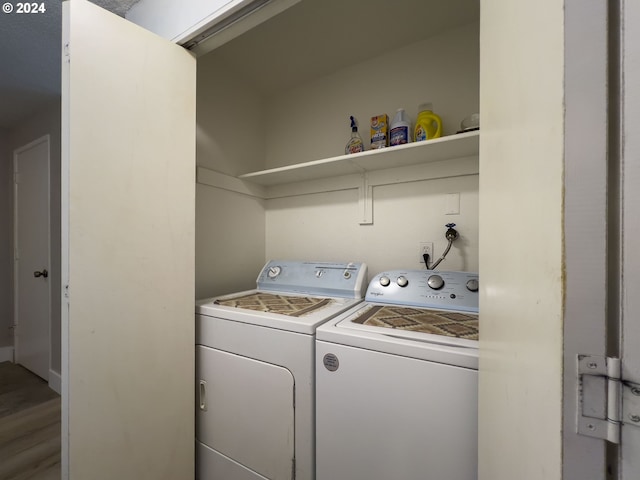 laundry area with washing machine and clothes dryer and hardwood / wood-style flooring