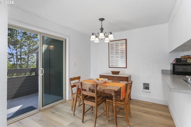 dining room featuring heating unit, a chandelier, light hardwood / wood-style floors, and a textured ceiling