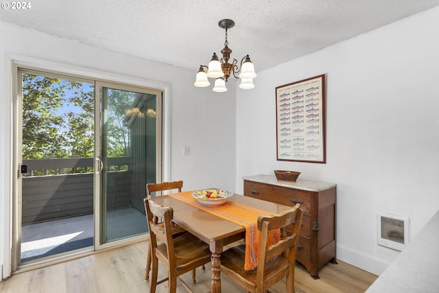 dining room with light hardwood / wood-style flooring, heating unit, a chandelier, and a textured ceiling