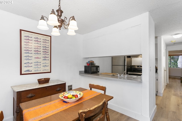 dining space featuring light hardwood / wood-style flooring, a textured ceiling, an inviting chandelier, and sink