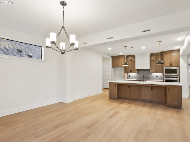 kitchen with sink, light wood-type flooring, appliances with stainless steel finishes, decorative light fixtures, and a chandelier