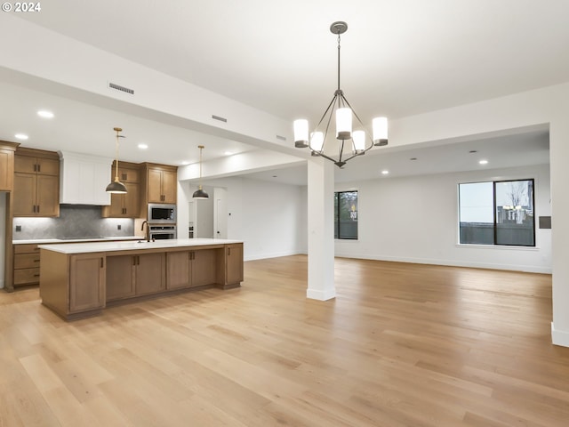 kitchen featuring light wood-type flooring, decorative light fixtures, and stainless steel appliances