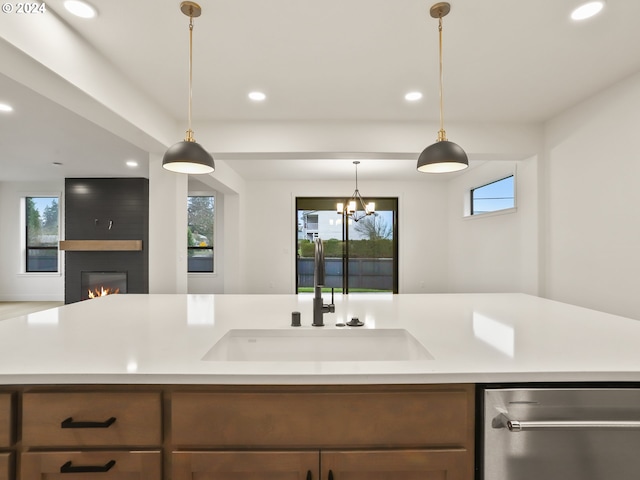 kitchen featuring a fireplace, an inviting chandelier, pendant lighting, and sink