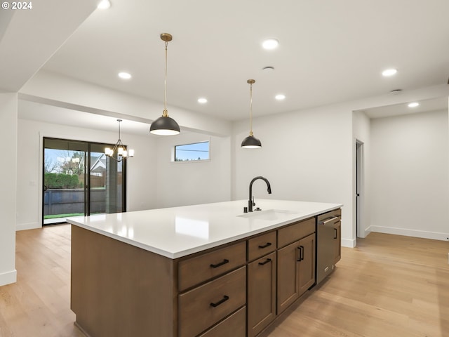 kitchen featuring stainless steel dishwasher, decorative light fixtures, sink, and light hardwood / wood-style flooring