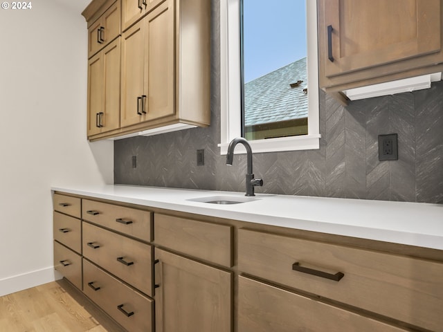 kitchen featuring tasteful backsplash, light hardwood / wood-style flooring, and sink