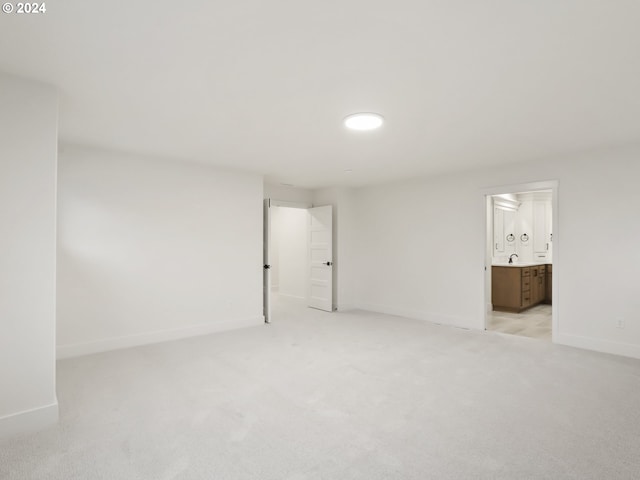 unfurnished bedroom featuring ensuite bathroom, sink, and light carpet