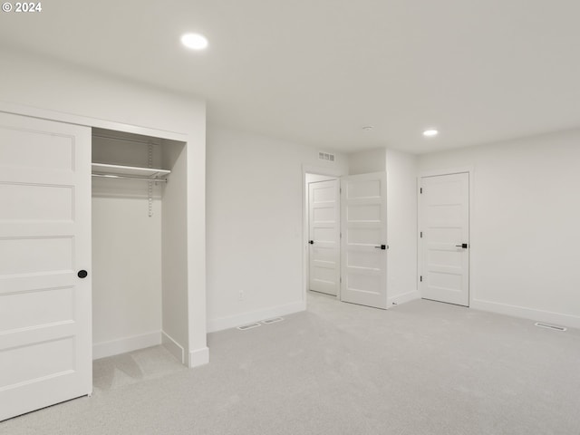 unfurnished bedroom featuring a closet and light colored carpet