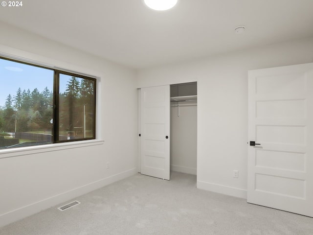 unfurnished bedroom featuring light carpet and a closet