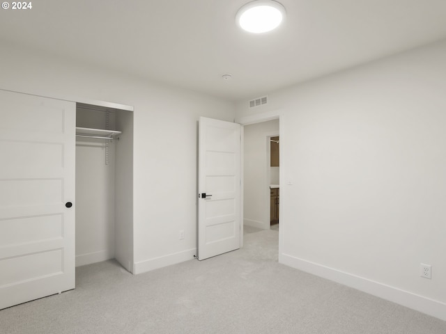 unfurnished bedroom with light colored carpet and a closet