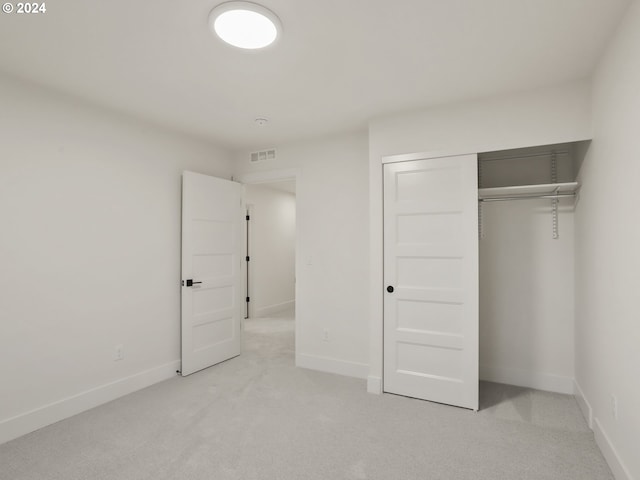 unfurnished bedroom featuring light carpet and a closet