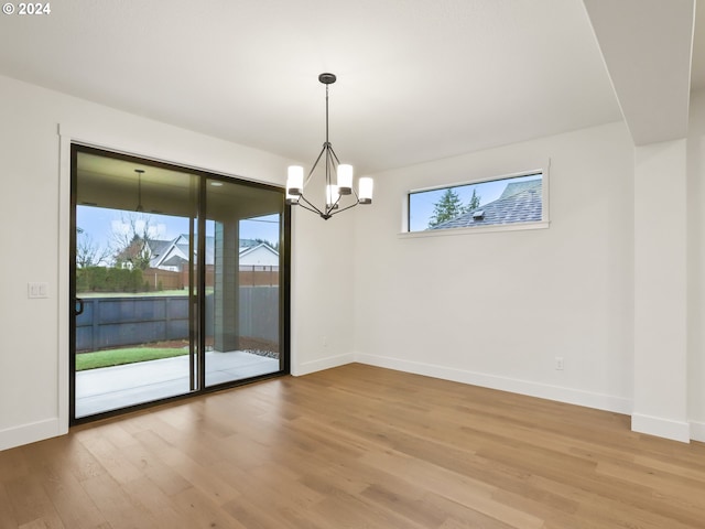 unfurnished dining area featuring hardwood / wood-style flooring and an inviting chandelier