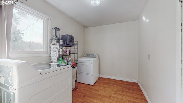 clothes washing area featuring light hardwood / wood-style floors and washing machine and clothes dryer