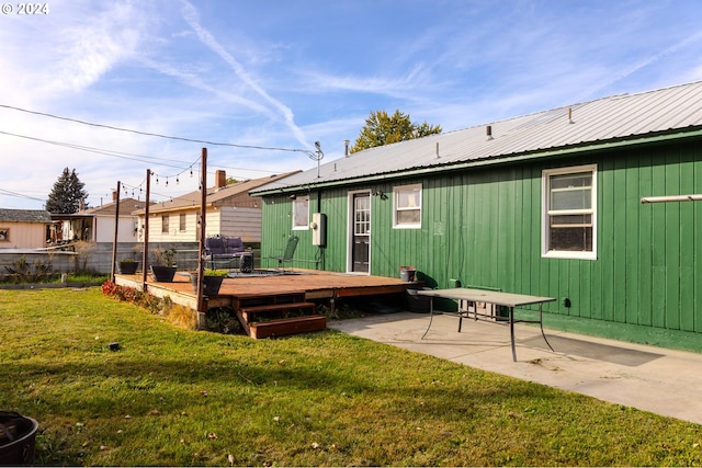 back of property with a wooden deck, a lawn, and a patio area