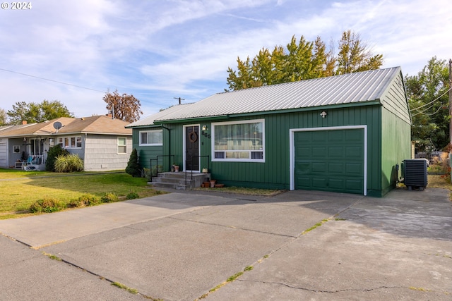 ranch-style home featuring a garage, a front lawn, and central air condition unit