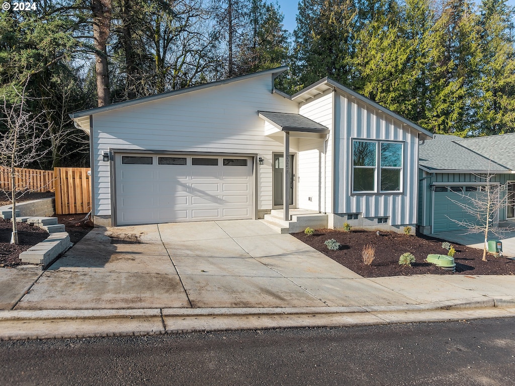 mid-century modern home with a garage, concrete driveway, and fence