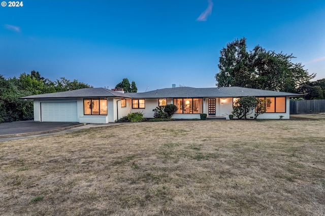 view of front of home with a garage, a lawn, fence, and aphalt driveway