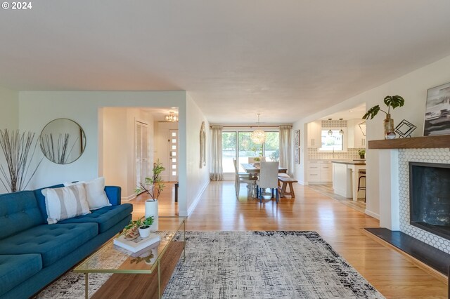 living room with light wood-type flooring and a tiled fireplace