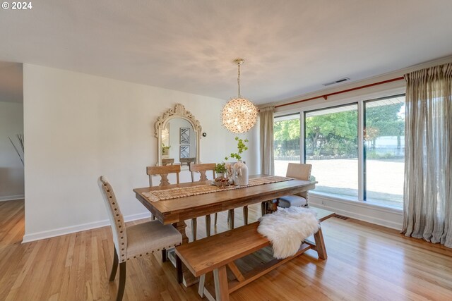 dining space featuring light wood-type flooring and a notable chandelier