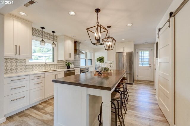 kitchen with a healthy amount of sunlight, wood counters, a center island, stainless steel appliances, and a barn door