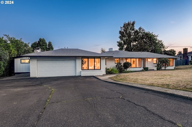 ranch-style home with a garage and a yard