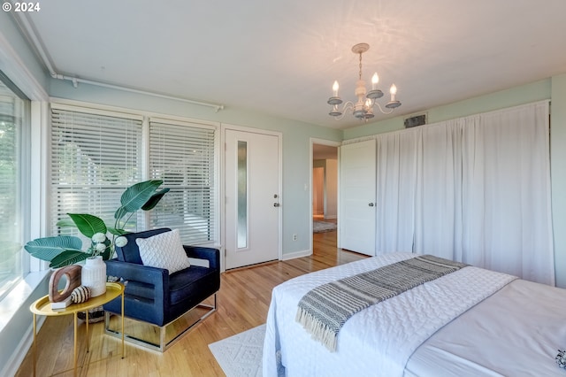 bedroom with a chandelier, light wood-type flooring, and multiple windows