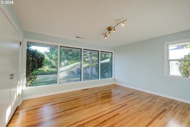 spare room with light hardwood / wood-style flooring, track lighting, and a healthy amount of sunlight