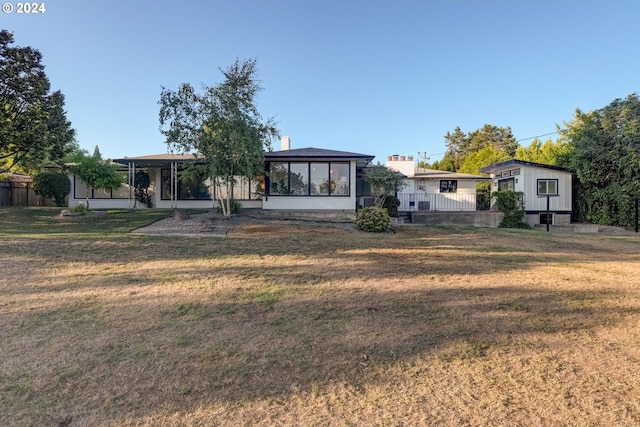 view of front of house featuring a sunroom and a front lawn