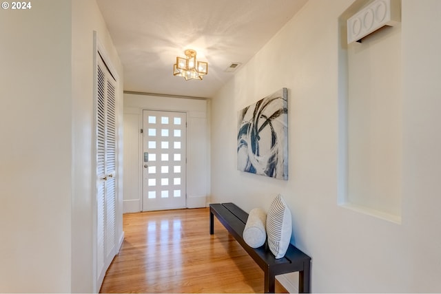 doorway to outside featuring light hardwood / wood-style floors and a chandelier